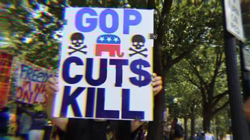 A protest sign that says ‘GOP Cuts Kill’ with skulls.